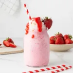 Creamy strawberry milkshake served in a glass jar with whipped cream and strawberry drizzle